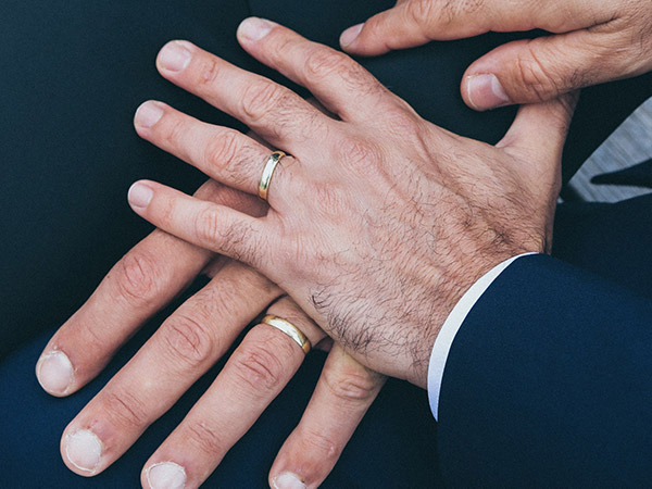 two-men-holding-hands-wedding-rings